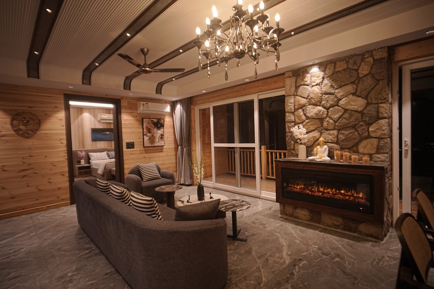 Living room with stone fireplace, chandelier, and balcony view